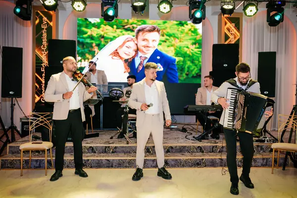 Formația pe scenă la o nuntă, cu mirii pe ecranul LED